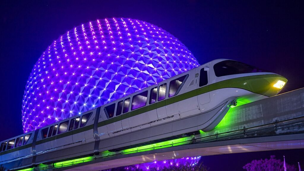 Spaceship Earth lit up at night behind monorail