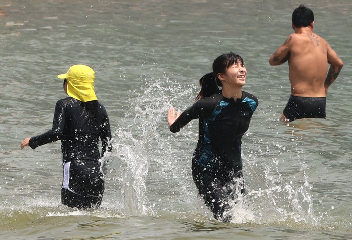 On the 29th, when a heat wave warning was issued in the eastern part of Jeju Island and a heat wave warning was issued between the north and the middle of the mountain, vacationers are enjoying the summer atmosphere by playing in the water or taking in the sea breeze at Hamdeok Beach in Jocheon-eup, Jeju-si. [Photo source = Yonhap News]