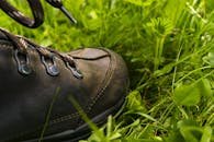 Leather hiking shoe close-up on vibrant green grass, perfect for outdoor exploration concepts.