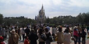 A large crowd of Disney fans walks towards Cinderella Castle at Tokyo Disneyland