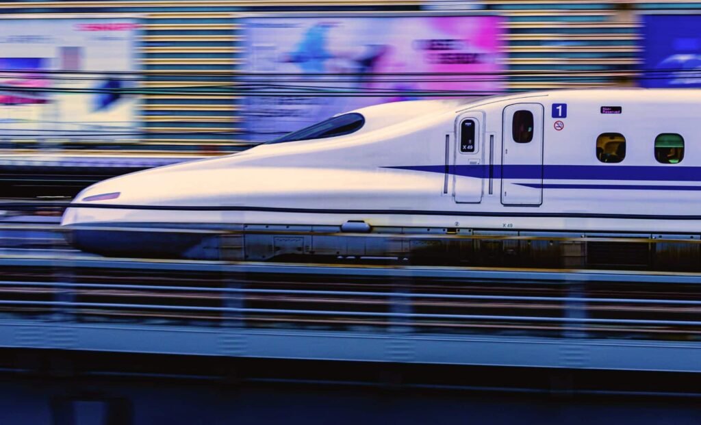 The Shinkansen Bullet Train Crosses A Station On A Rainy Day In Tokyo's Megalopolis
