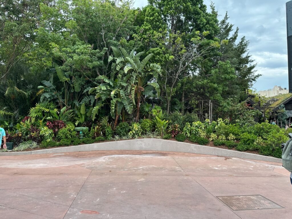 Visitors walk near the Royal Sommerhus under cloudy skies at a themed amusement park area with landscaping and buildings.