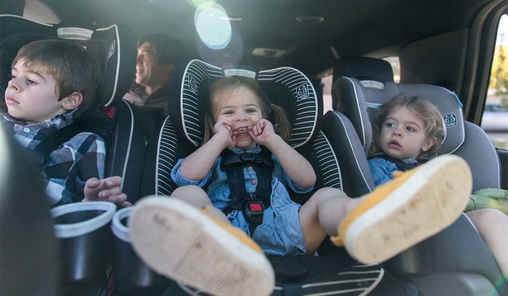 Three siblings strapped into carseats being silly; Shutterstock ID 2423152637; purchase_order: -; job: -; client: -; other: -