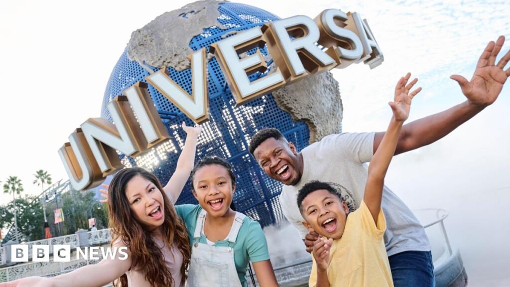 A large blue globe on display outside a Universal theme park in the USA, with four people outside with their mouths open and arms outstretched.