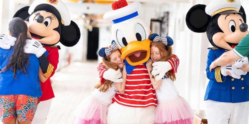 Three children hug Disney characters Minnie Mouse, Donald Duck, and Mickey Mouse, who are dressed in nautical costumes on a brightly lit cruise ship deck—a magical moment and the perfect start to an adventure filled with Disney Cruise Tips.