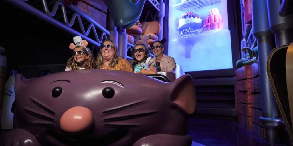A family of four wearing 3D glasses rides a "Ratatouille" themed attraction at Walt Disney World in 2025. They are seated in a rat-shaped vehicle, surrounded by oversized kitchen items, creating the illusion of being in a giant kitchen during Disney After Hours.
