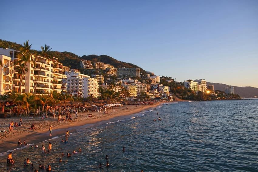 Tourists swim and lounge on the beach in front of Puerto Vallarta hotels and condos