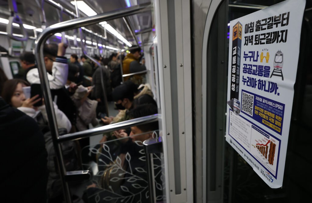 Commuters sit and stand inside a subway car in Seoul on Dec. 1, 2025. [YONHAP]
