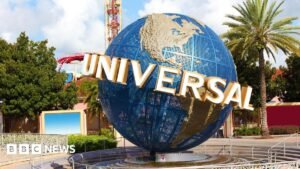 A view of the Universal globe outside the entrance to the Florida park. A roller-coaster and other rides can be seen in the background.
